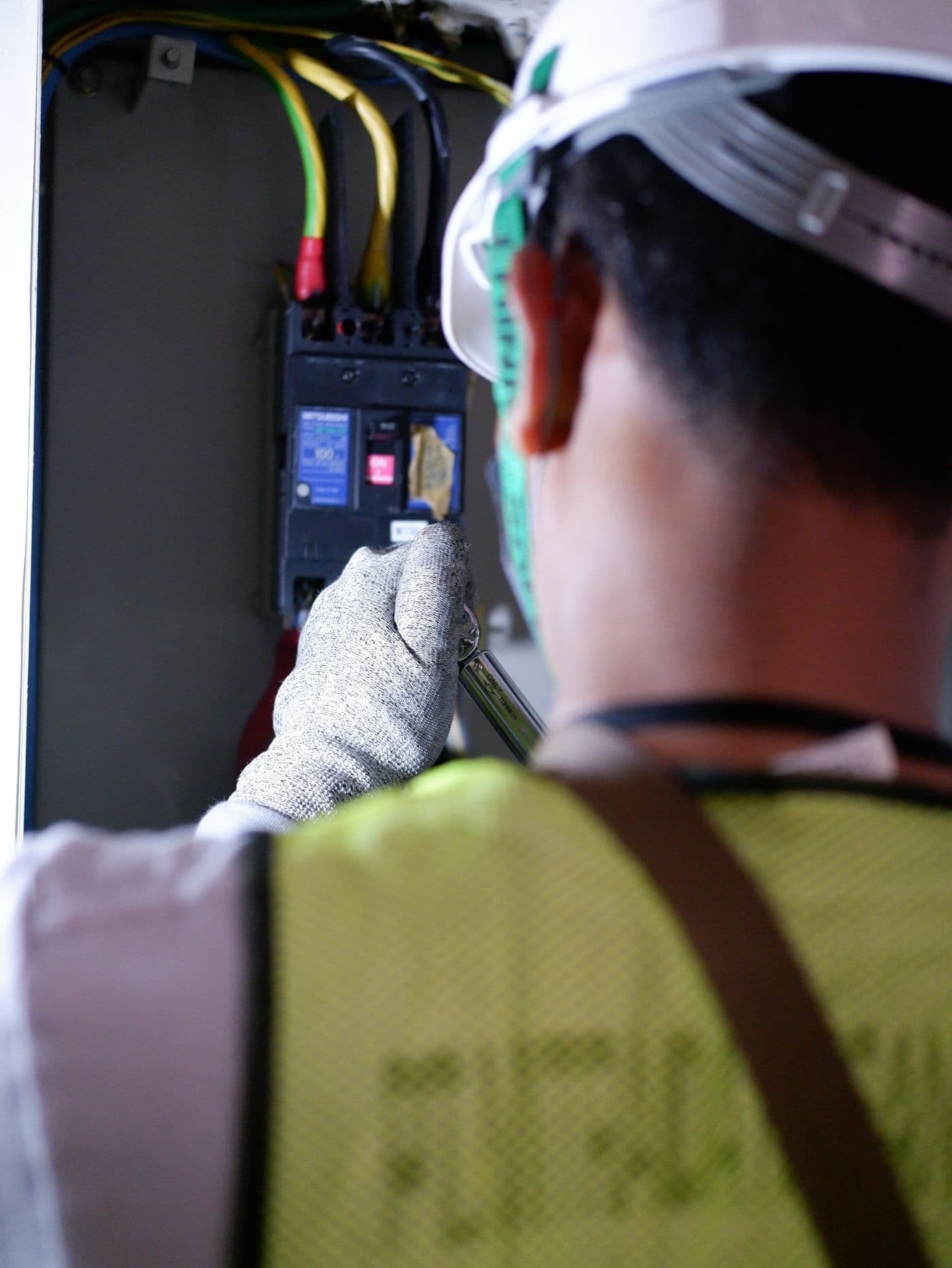 Electrician working safely inside a breaker box